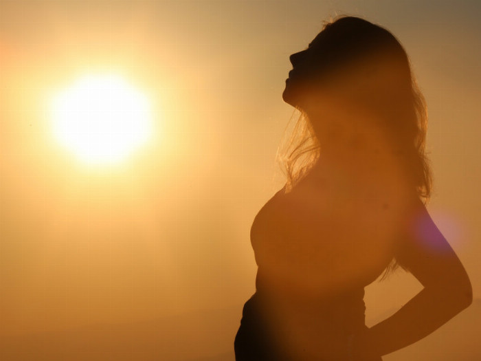 Žena stojí ve světle západu slunce. Profil ženy. Silueta ženy ve světle