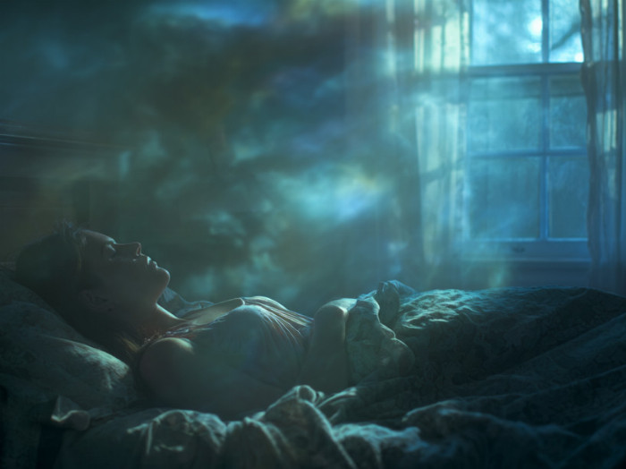 Spící žena v posteli. Měsíční svit.