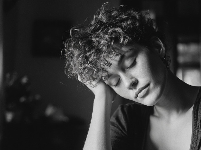 Usmívající spící žena si podepírá rukou hlavu