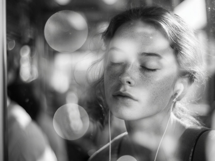 Mladá žena se zavřenýmia očima a se sluchátky na uších