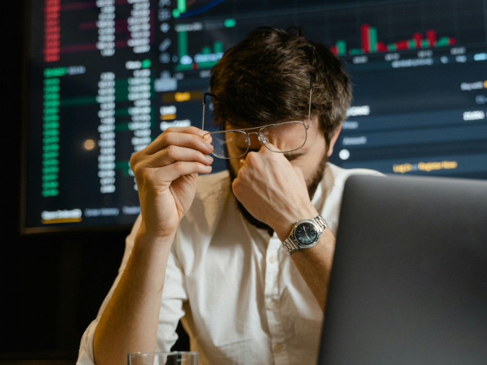 Unavený muž za pracovním stolem, který si mne oči